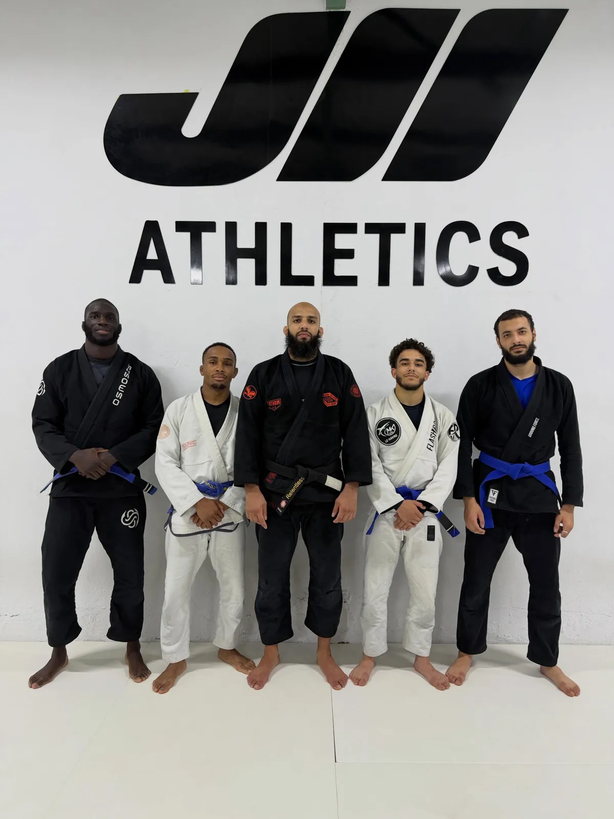 Cinq athlètes en kimono devant le mur JII Athletics